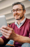 A man with a tablet in his hand looks at the onOffice Online Marketing Consulting website.