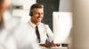 Lächelnder Mann mit Headset vor Computer