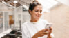 Frau die auf ihrem Smartphone Online Marketing für Immobilienmakler prüft