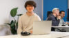 Junge der hinter dem PC sitzt und in die Kamera lächelt