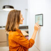 Frau die am Tablet ihr Zuhause steuert