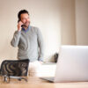 Mann der telefoniert mit Laptop und Tablet vor sich
