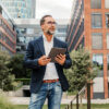 Ein Mann steht mit seinem Tablet vor einem Gebäude