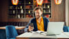 Mann in einem Café am Laptop mit Smartphone in der Hand