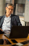 Mann der am Laptop die passende Immobiliensoftware auswählt