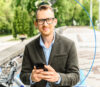 Mann mit Handy in der Hand der in die Kamera lächelt